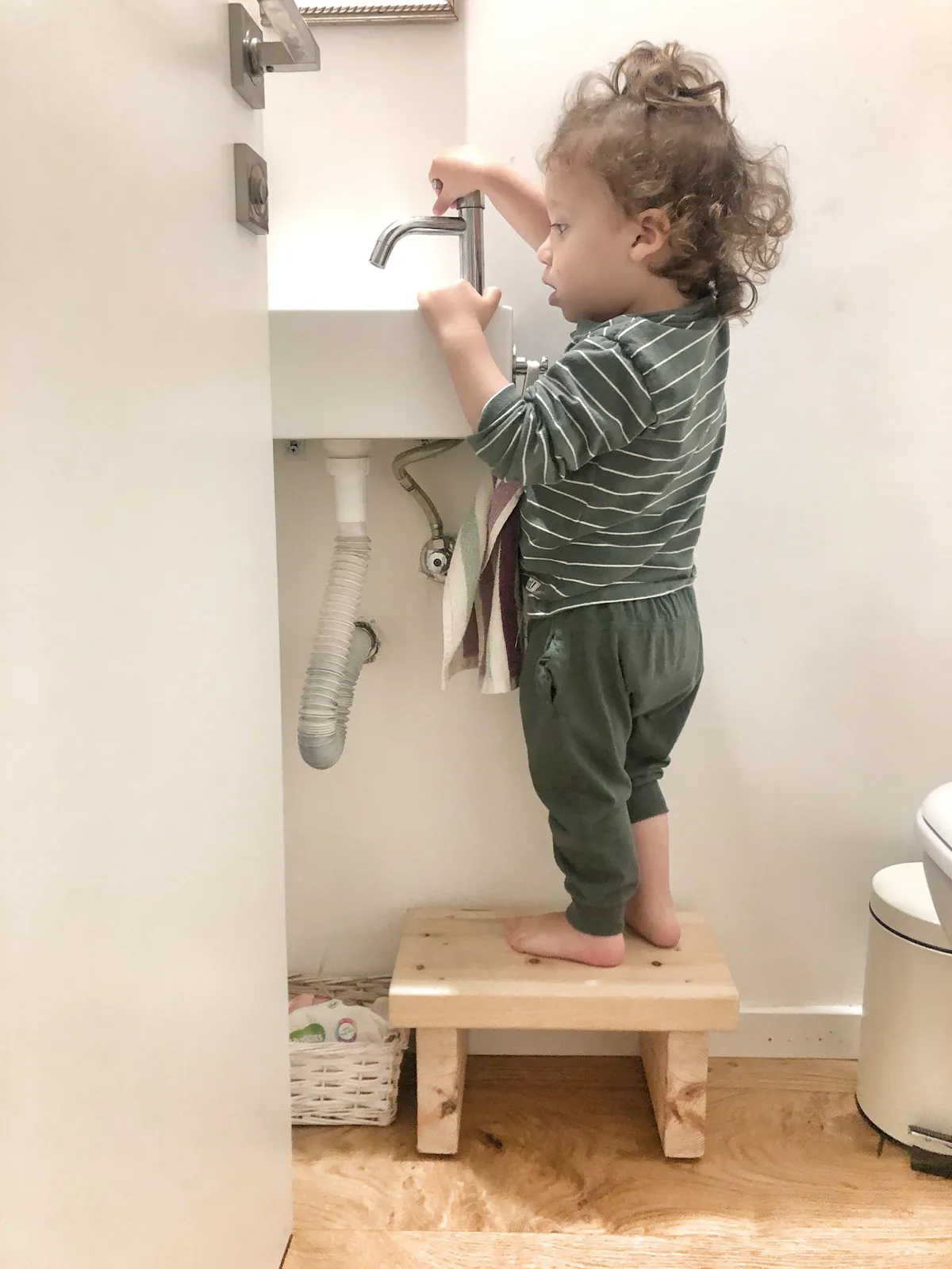 ילד משתמש בשרפרף כדי להגיע לברז בכיור