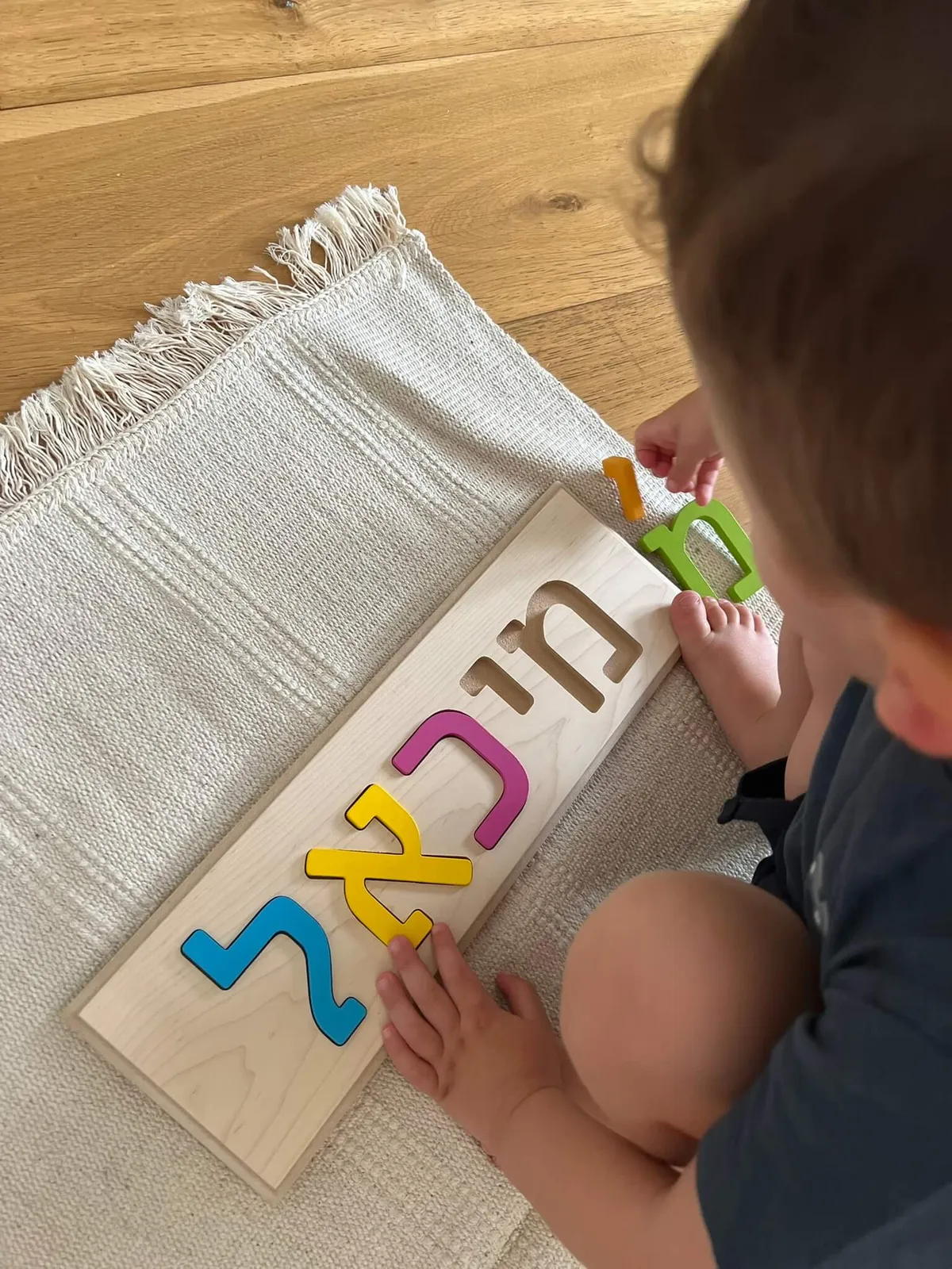 ילד משחק עם פאזל שם עשוי מעץ